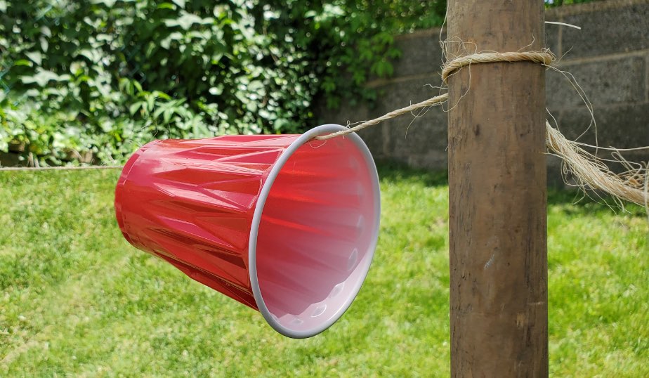 red plastic cup secured to a post with string